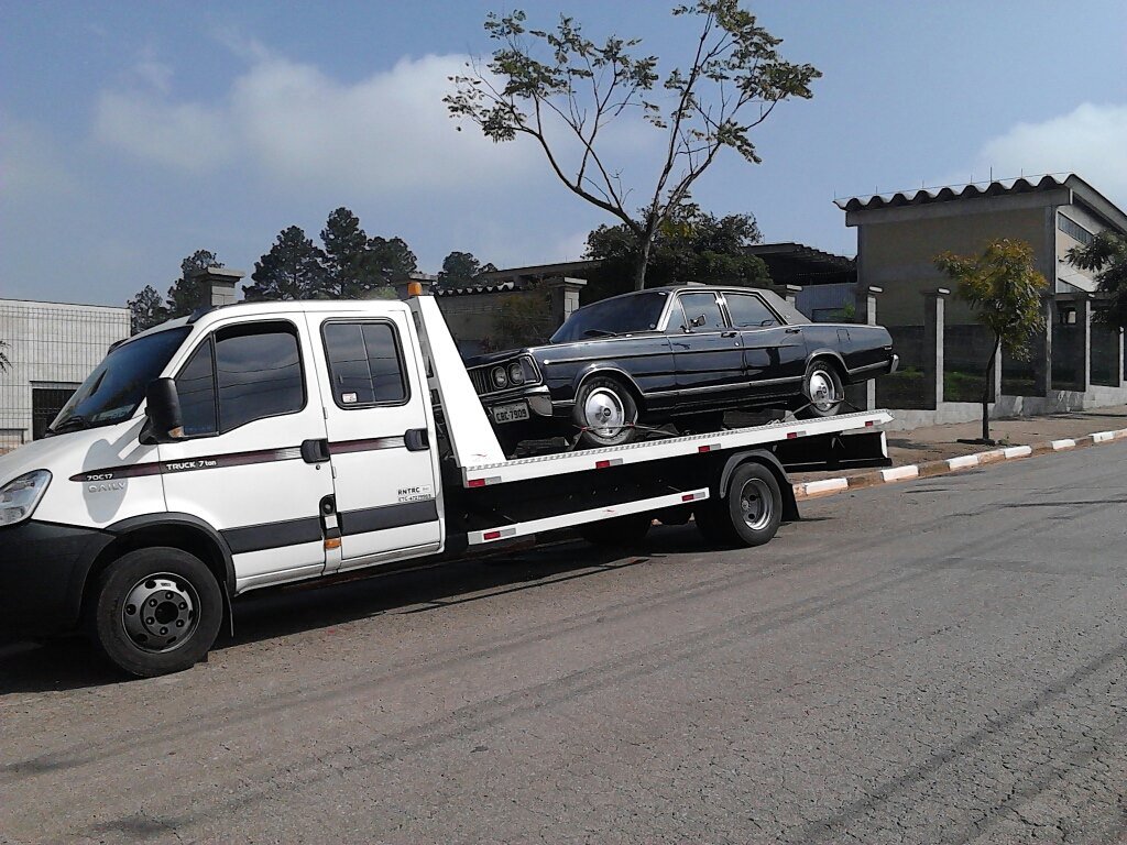 Caminhão guincho plataforma transportando um carro